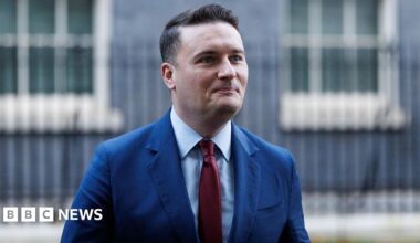 Health Secretary Wes Streeting wearing a blue suit and red tie leaves Downing Street on 2 December 2025.