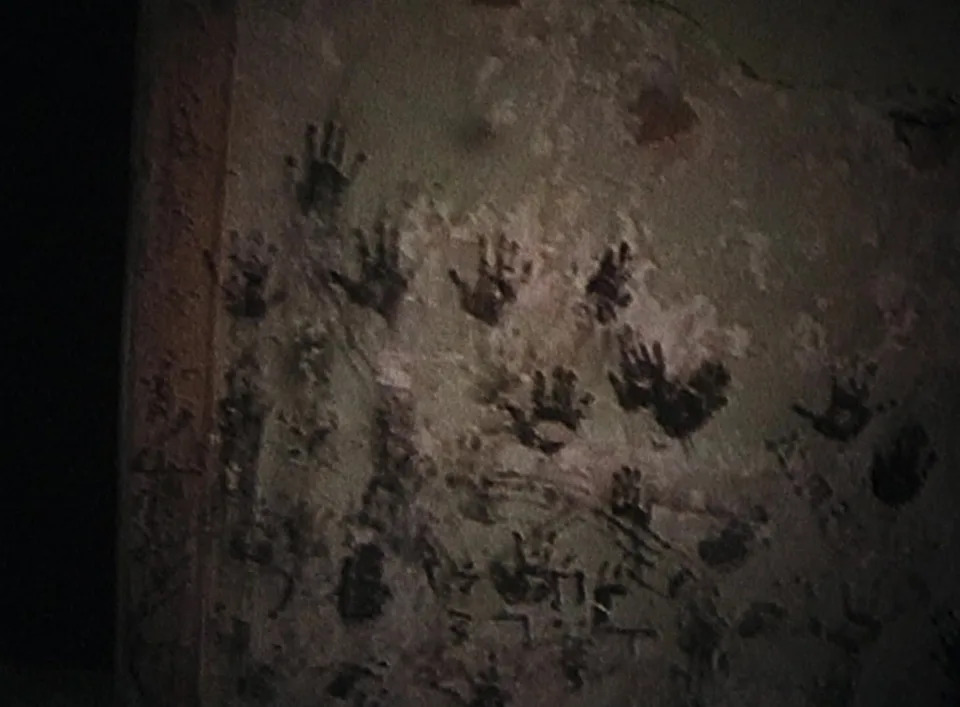 Multiple handprints on a textured wall, possibly in artistic or historical context