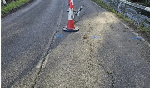 North Lincolnshire Council Image showing the damage to the road, There are a number of large cracks, as well as traffic cones and blue paint marks on the carriageway.