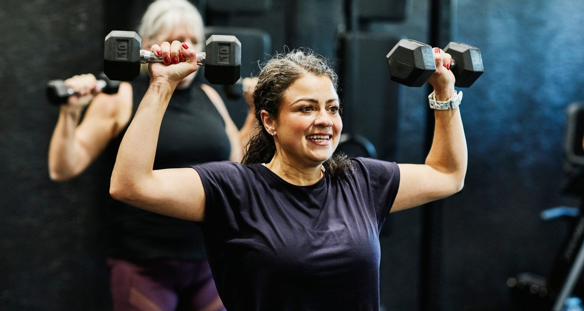 Woman doing overhead press as part of the 2-2-2 workout in the gym