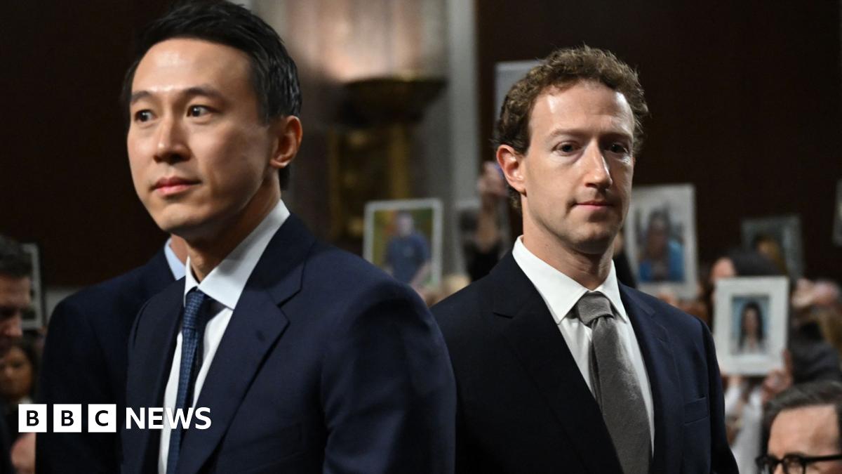 A brown NC500 sign post which says it is 27 miles to Ullapool next to a country road with hills in the background.