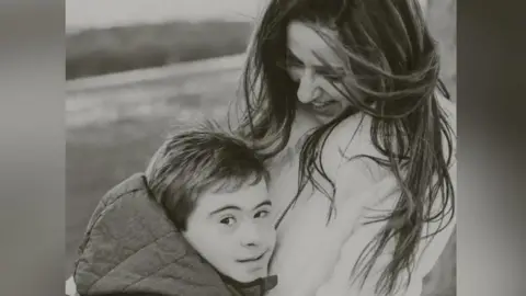Leigh Day Antonio (L) with his mother Milena (R) in a black and white photo on what appears to be a beach or countryside. 