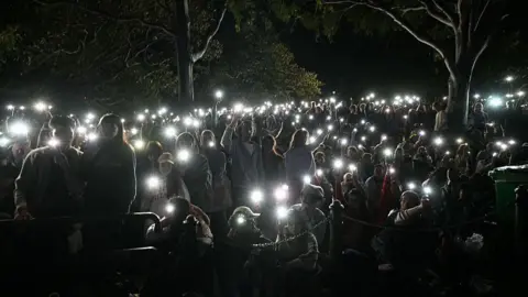 AFP via Getty Images it is dark with all the light coming from the hundreds of mobile phones being held up in the air
