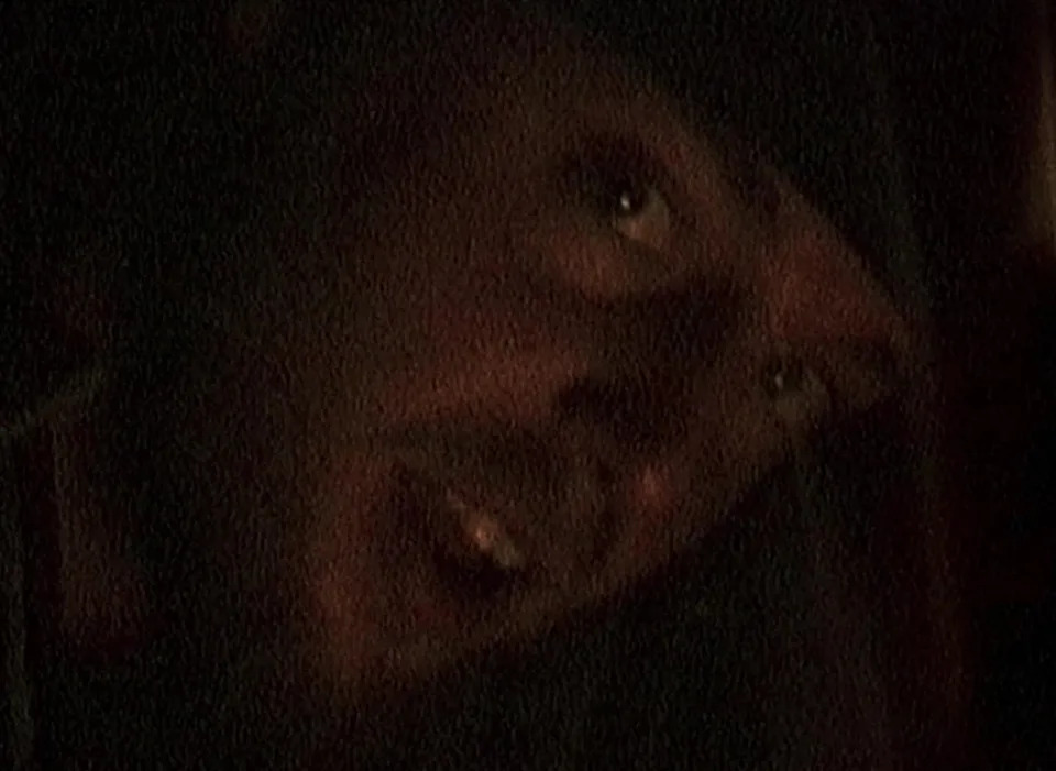 A person with a surprised expression is partially visible in a dimly lit setting
