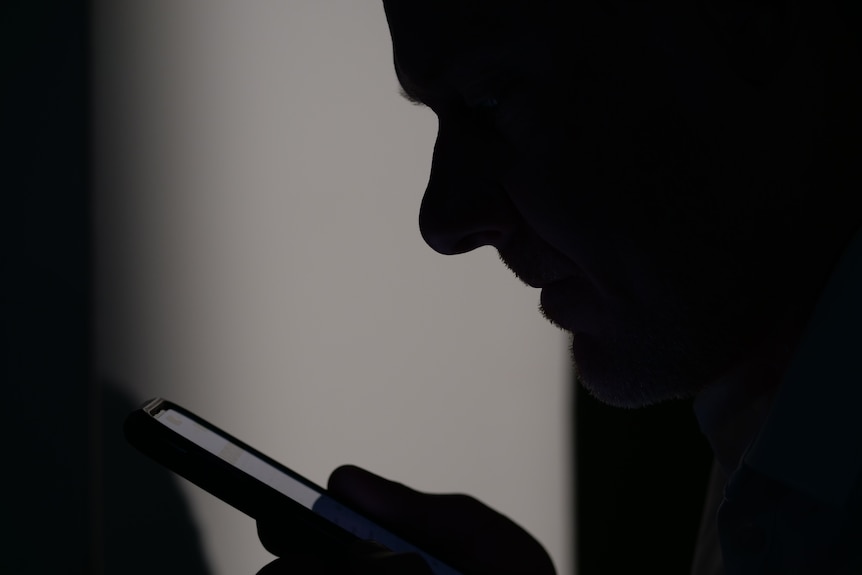 a silhouette of a man using a smart phone.  