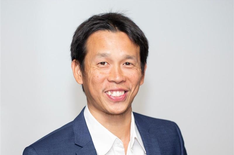 A middle aged man in a suit smiling for a corporate headshot. 