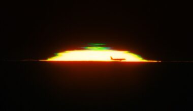 The half dome of a glowing sunset is seen against a black sky with the silhouette of an airplane in the front and a green shape above it.