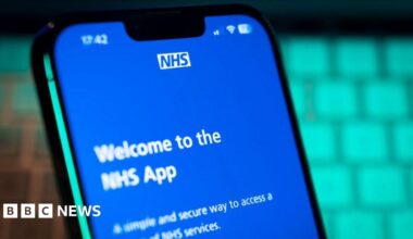 A phone with a blue screen on it. The screen has white writing on reading "Welcome to the NHS app".