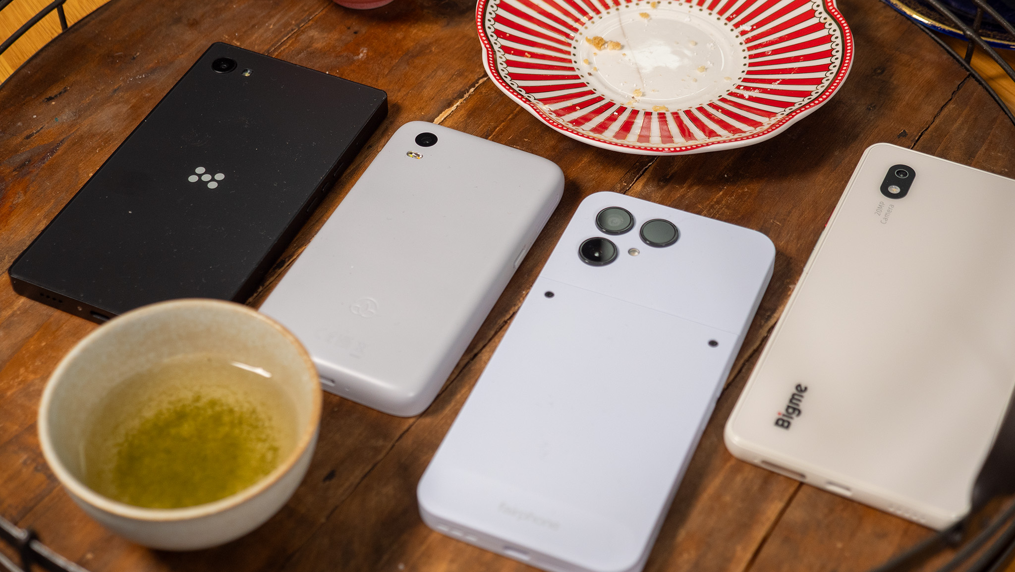 Three E Ink Phones and the Fairphone 6 on a tea tray