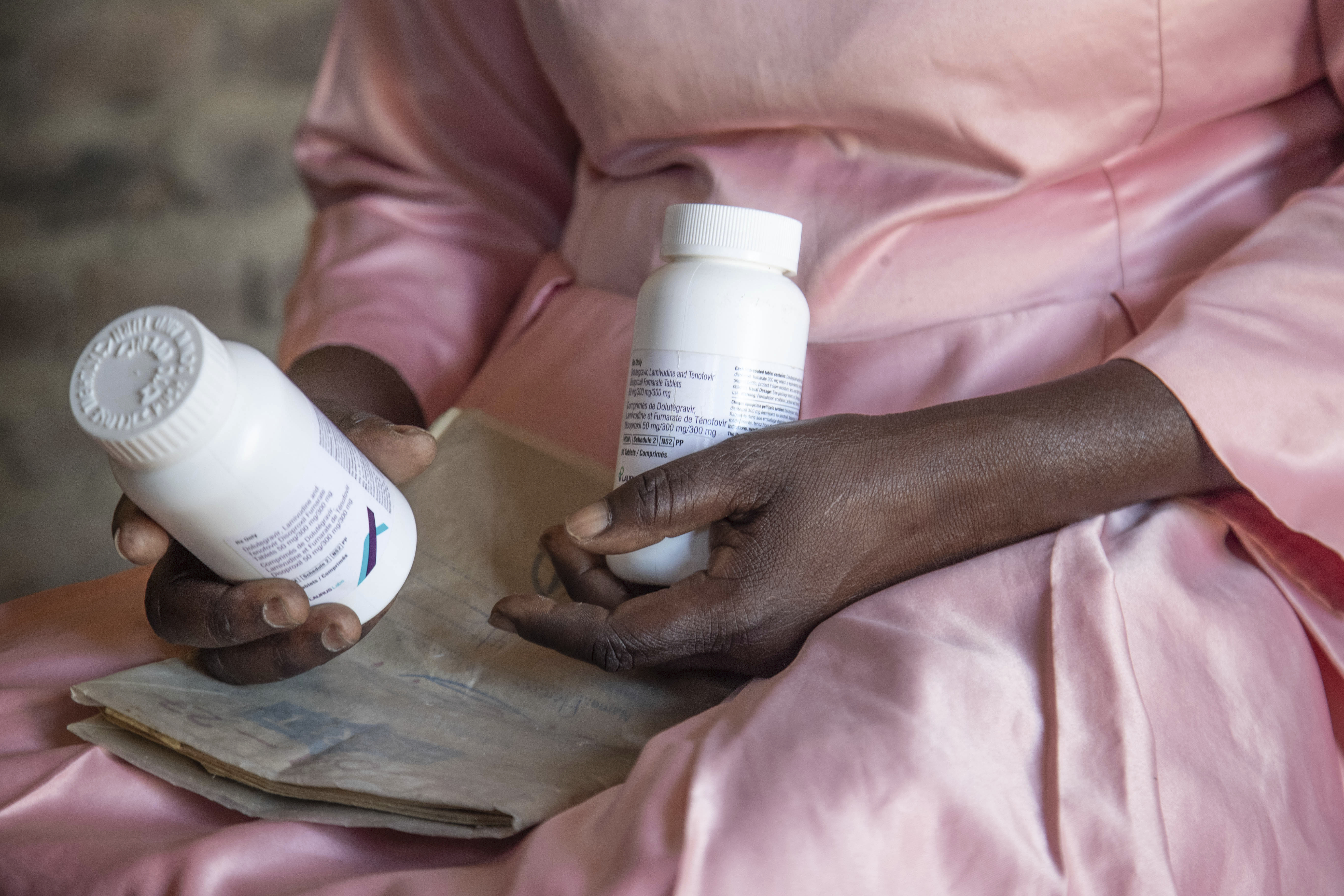 A woman holds her HIV medication and a hospital records book at her home in Harare, Zimbabwe, Friday, Feb. 7, 2025.