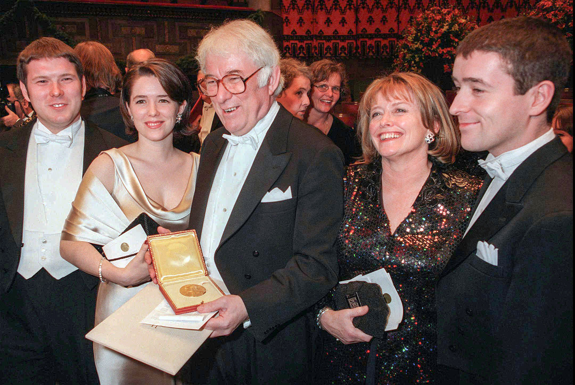 Poet Seamus Heaney surrounded by family holding Nobel medal.