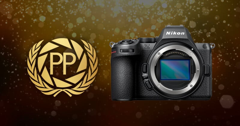 A Nikon Z camera body is displayed next to a gold laurel wreath emblem with the letters "PP" on a dark, sparkling background.