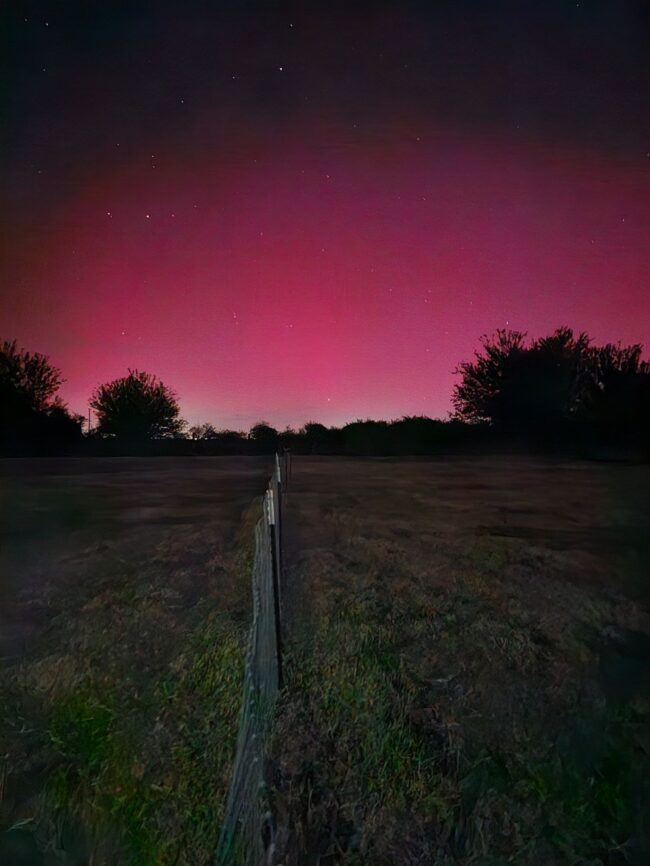 A reddish glow brightens the horizon of a dark landscape.