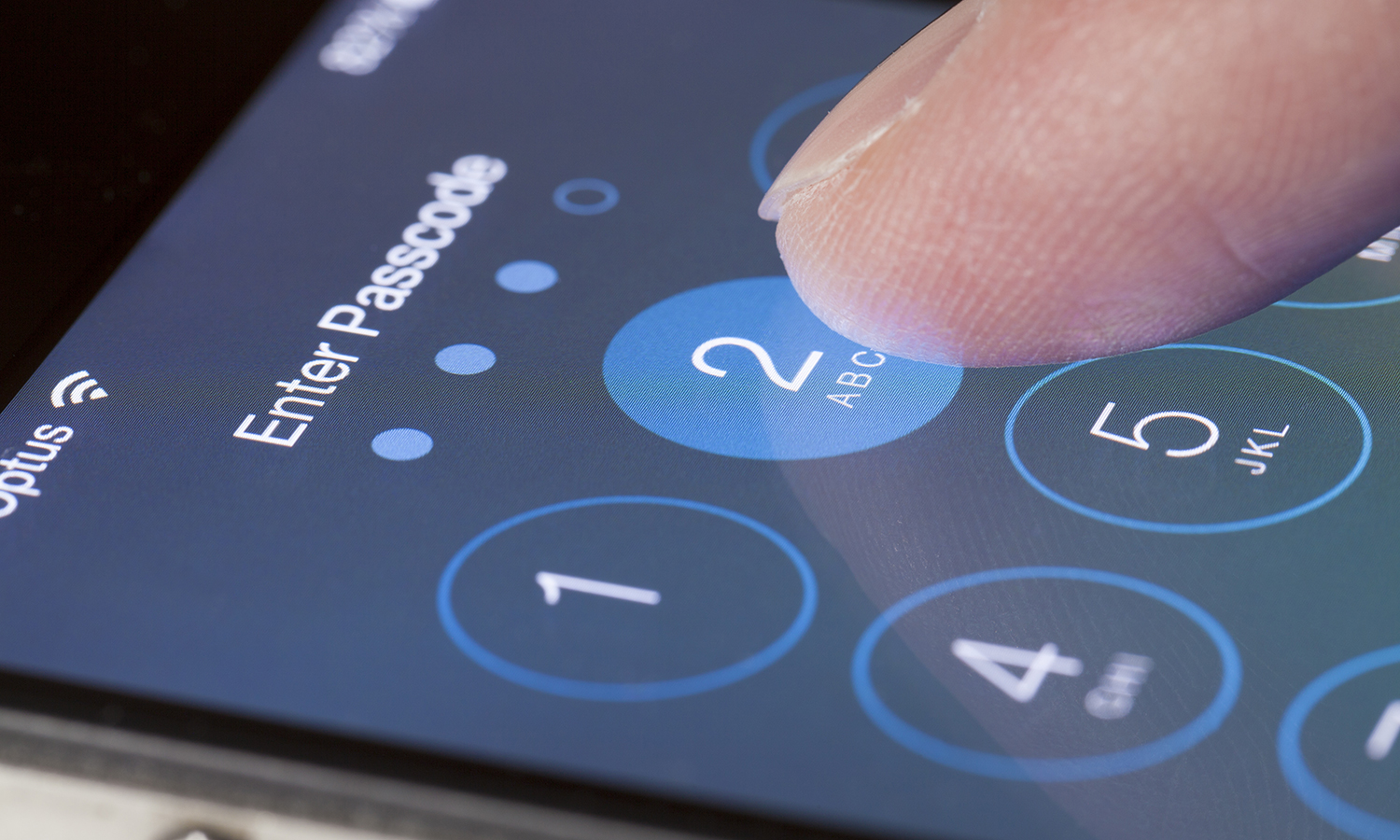 Finger typing passcode into iPhone screen.