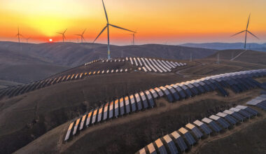 The sun sets behind wind turbines and rows of solar panels at a renewable energy farm in Qingyang, China. Credit: Chen Kun/VCG via Getty Images