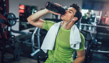 Young man drinking pre-workout drink from bottle in the gym
