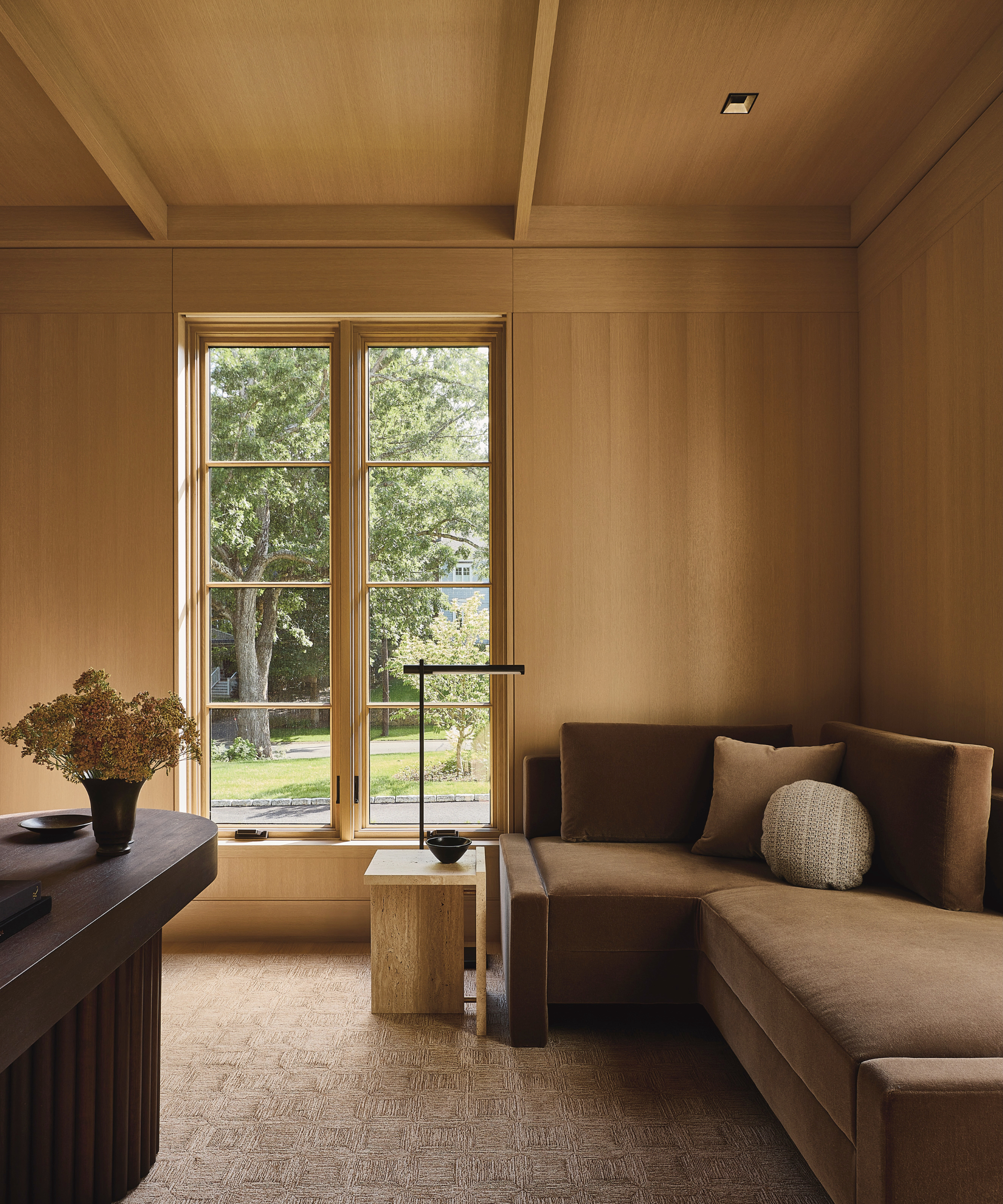 An office with oak paneled walls and a brown L-shaped couch.