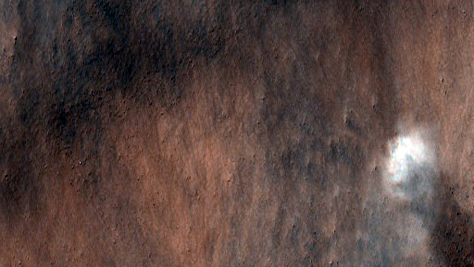 An overhead view of the surface of Mars, as a white dot swirls over the red dust