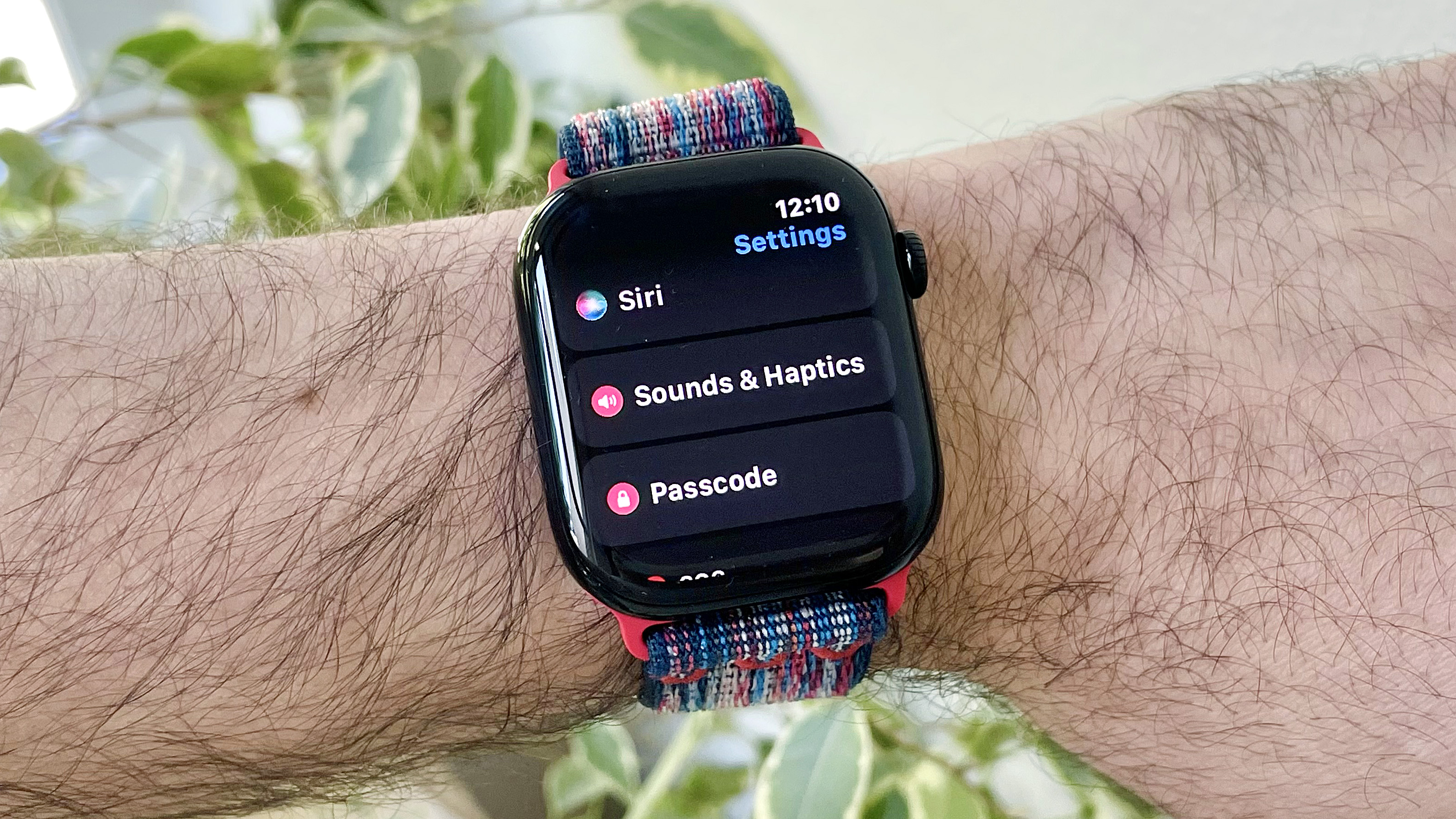 Close-up of a user's wrist wearing the Apple Watch Series 10 running the latest watchOS 26 software. The screen shows the new Automatic Audio Adjustments setting