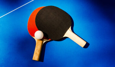 Two ping pong paddles overlapping on a ping pong table with a white ping pong ball.