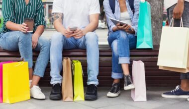 people sitting down holding phones and paper cups with paper shopping bags at their feet