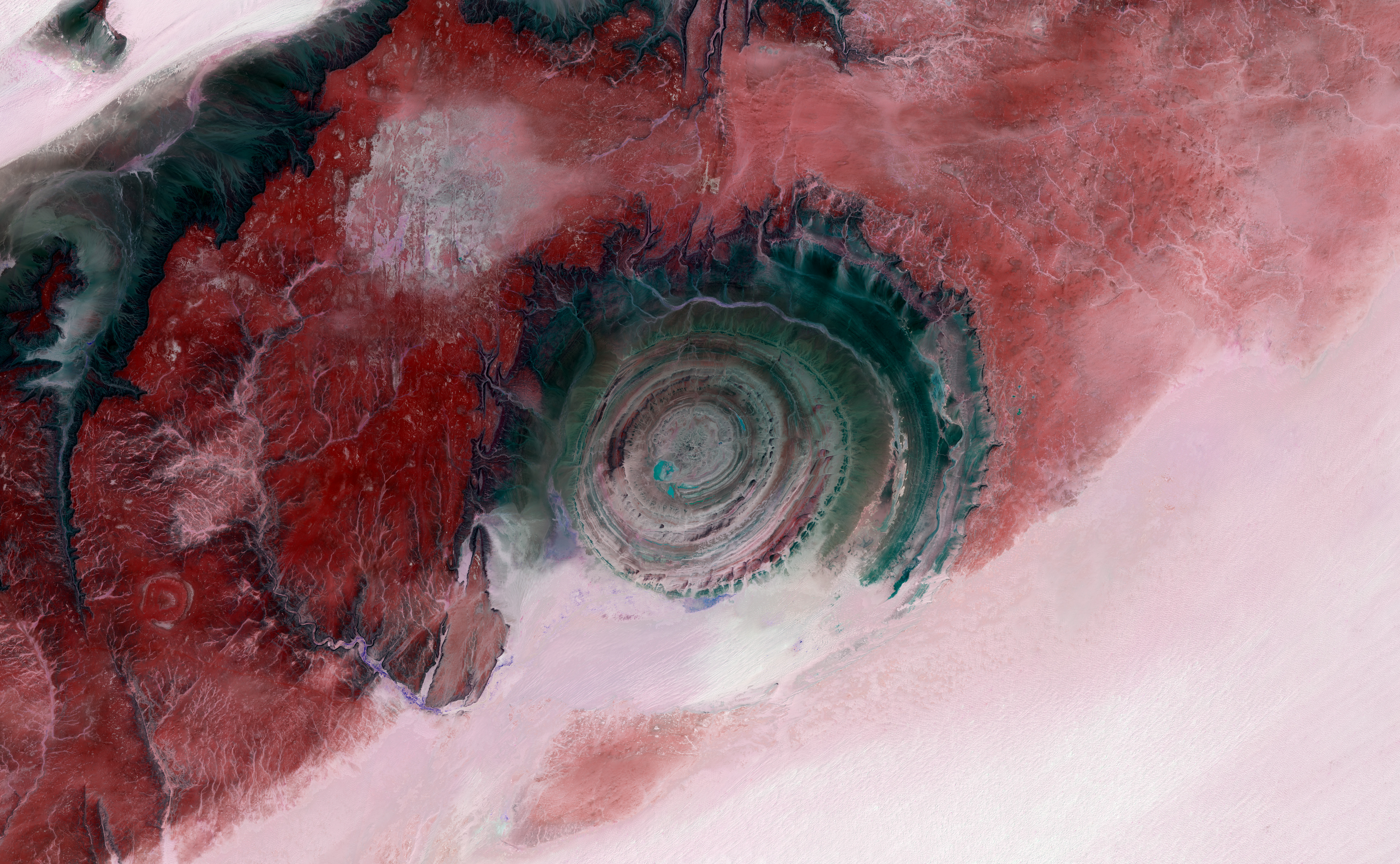 A dark circular eye peers out of a lighter landscape of the Saharan Desert