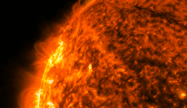 In this animated GIF, a portion of the Sun appears in shades of orange, yellow, and black with the brightest regions appearing yellow. The Sun appears against a black background. On the upper left edge of the Sun a bright flash of yellow appears, a solar flare, and then a plume of yellow and orange material rises away from the Sun from the same location as the flare.