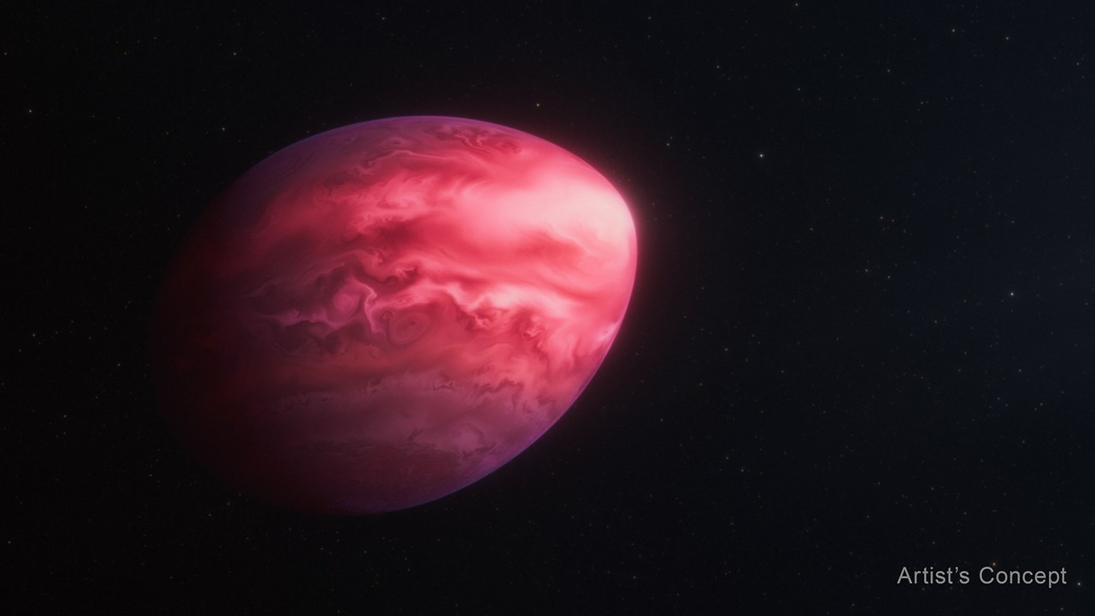 Partially illuminated, lemon-shaped planet appears against a black background. The planet is most brightly illuminated at its elongated tip on its right side. On the left side, which is wider, the planet trails off into the darkness of the background. The planet is colored in varying, mottled shades of red, light pink, and fuchsia. Most of the pink occurs closest to the tip, while most of the fuchsia is at the top and bottom edges.