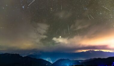 Shooting stars are pictured streaking downwards through a starry sky towards a cloudy horizon lined with mountains, lit in a blue mist.