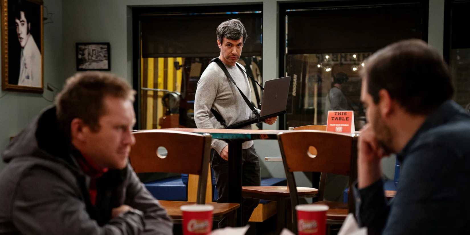 A conversation between two men while Nathan Fielder creepily watches in the background, taking notes from his mobile laptop setup, in The Rehearsal
