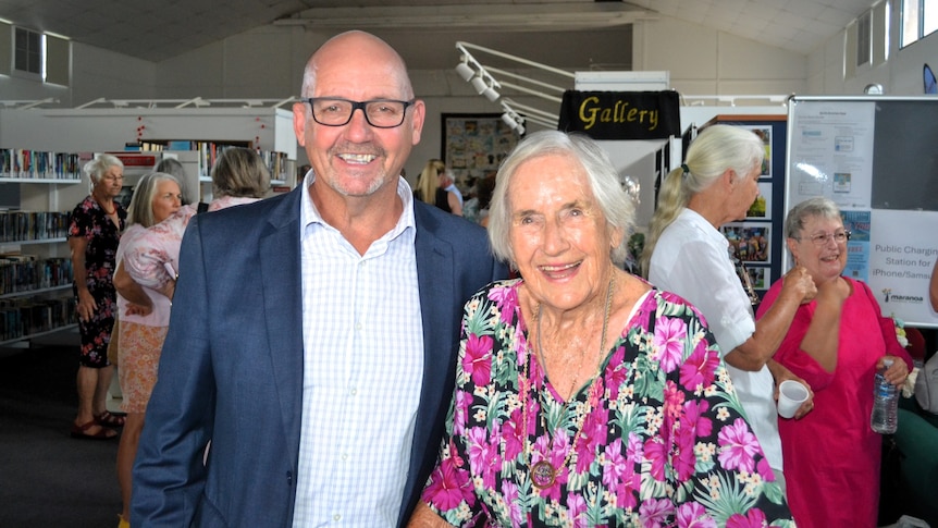 Marion Moore at her art exhibition standing next to man in a blue suit