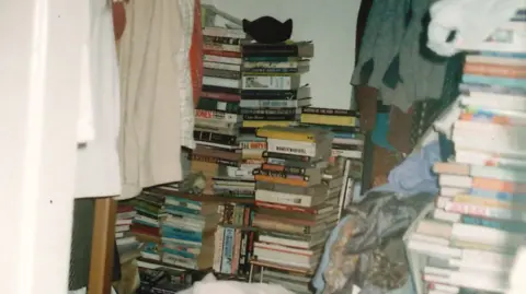 Handout The bedroom of a person with hoarding disorder, stacked high with piles of books and clothes.