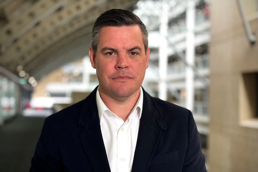 Middle age man with dark hair wearing white shirt and dark jacket