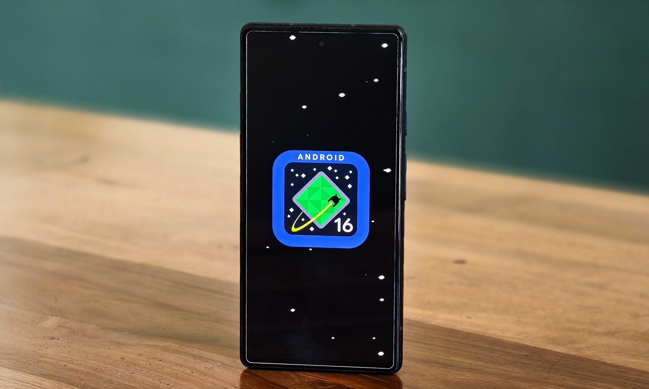 Android 16 logo on Google Pixel 6a standing on a table.