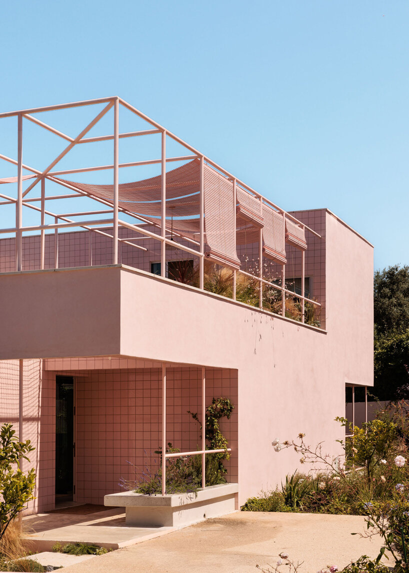atelier RUA's light pink house contrasts with surrounding greenery in portugal