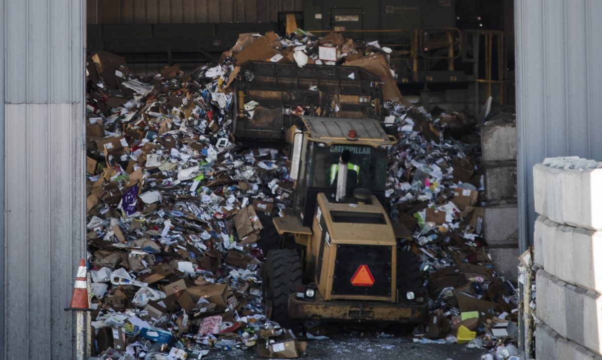 A giant truck pushes recyclables into a warehouse