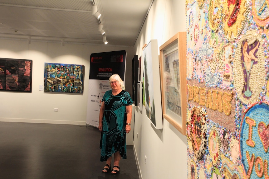 Hellen Dennis stands amongst an exhibition at the Lapunya Art Gallery. 