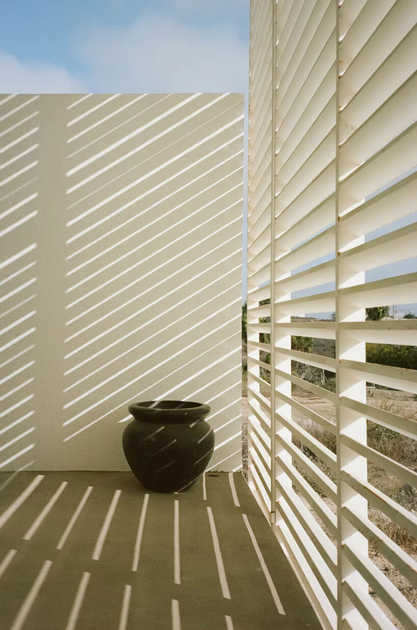 white louvers craft perforated facade filtering daylight within casa nada’s interiors in mexico