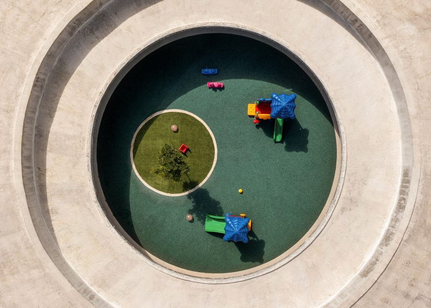 Aerial view of a ring-shaped concrete building with a central outdoor play area