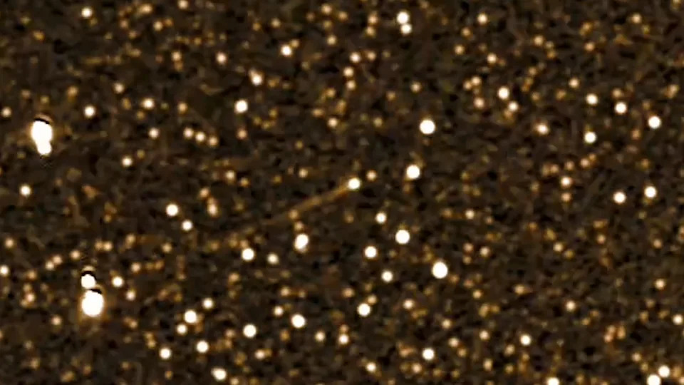 A streak of white light is seen amidst a starry golden deep space image