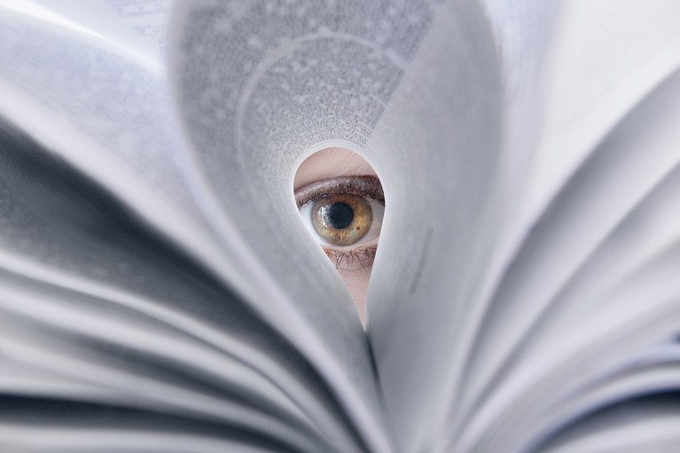 A person’s eye looking through looped-over printed pages in a journal.