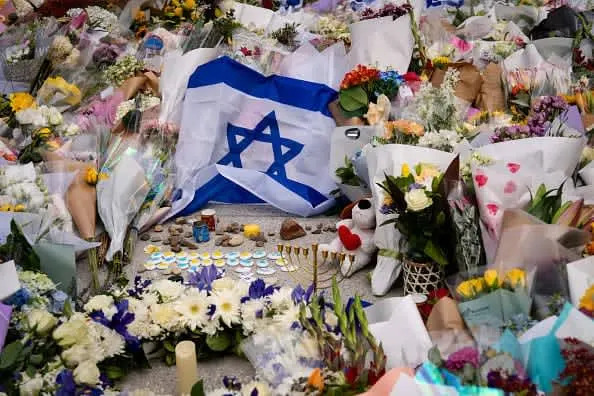 An Israeli flag and flowers are laid outside Bondi Pavilion at Bondi Beach as people gather to mourn in the wake of a mass shooting on December 15, 2025 in Sydney, Australia. (photo credit: Audrey Richardson/Getty Images)