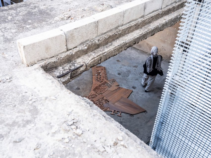 Bird's eye view photo of a woman walking through an exhibition as viewed through a gap in the floor above