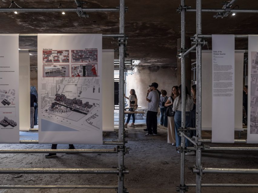 Photo of architecture exhibits within a dark and simple exhibition space on scaffolding display units