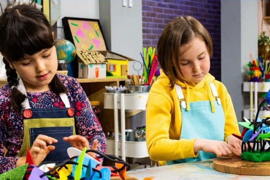 Three children are calmly engaged in making crafts at a table in a classroom
