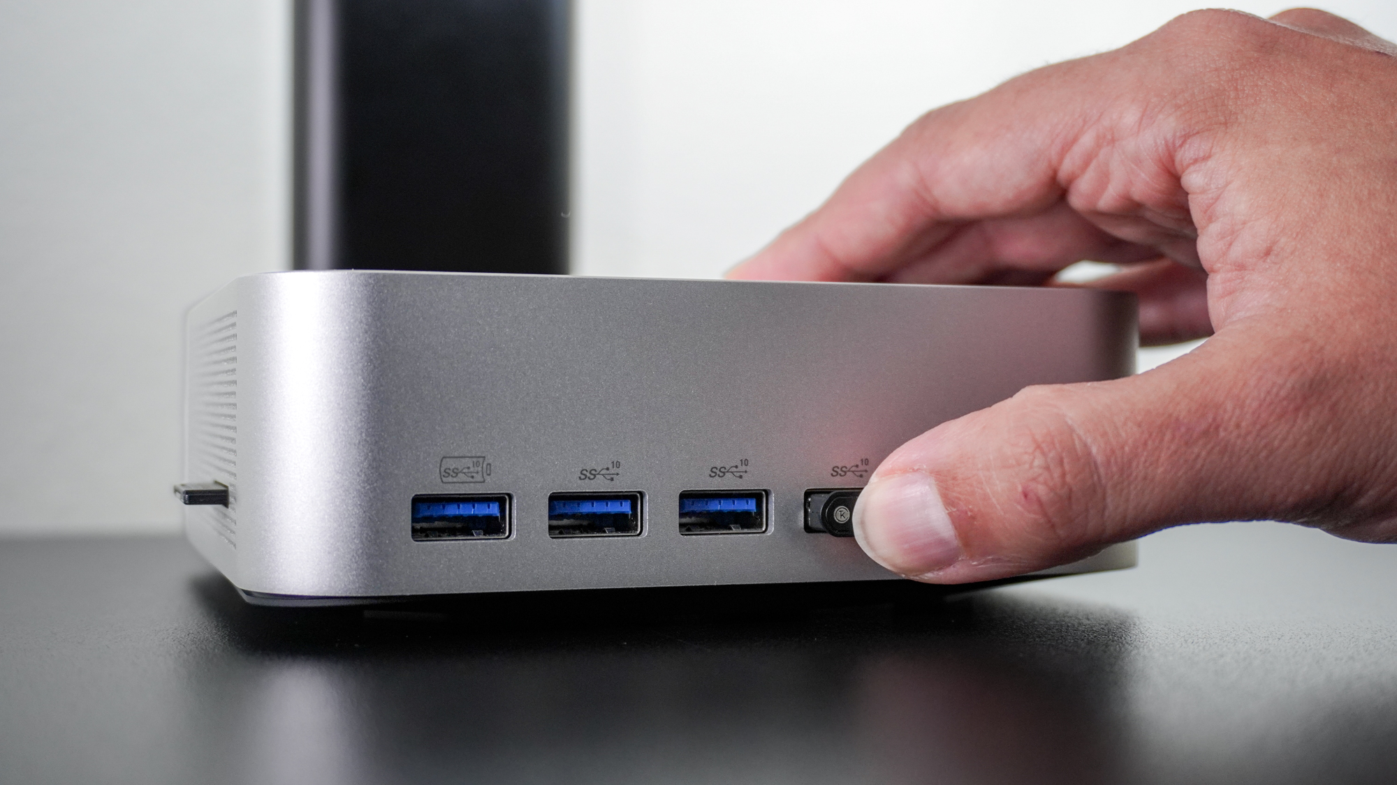 A person inserting a 2.4 GHz USB dongle into one of the front ports of the Geekom A9 Max