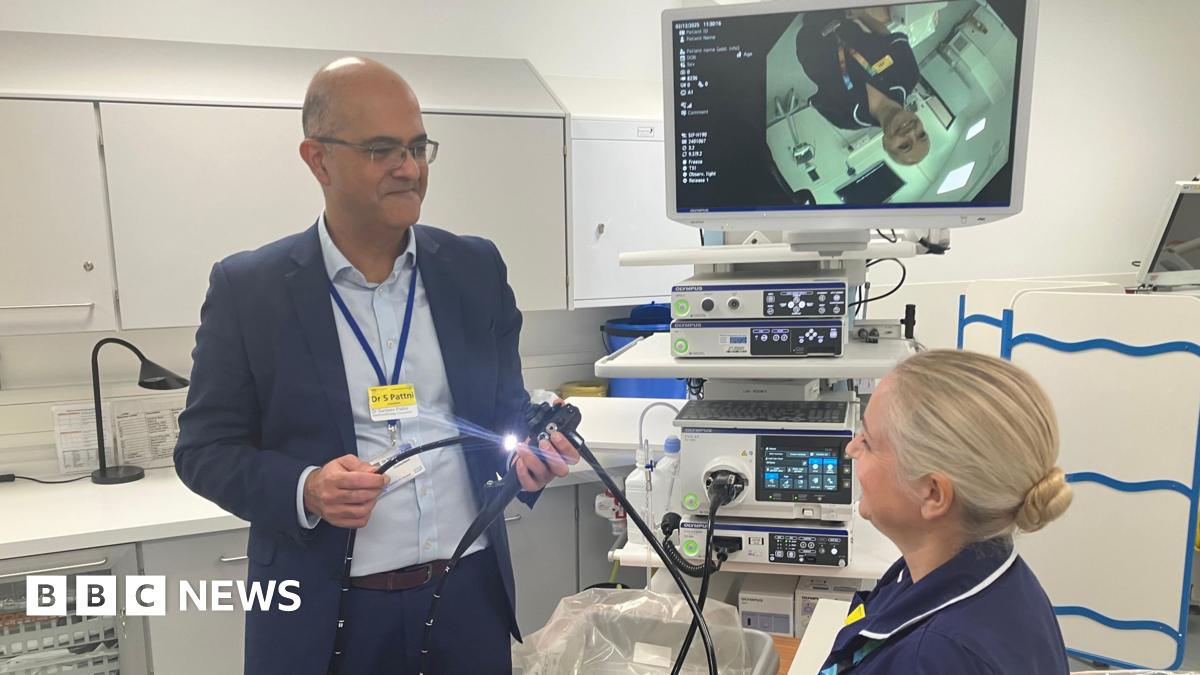 Dr Sanjeev Pattni, a consultant Gastroenterologist and co-head of service at Leicestershire's Hospitals, showing a nurse the endoscopy equipment in a medical room.