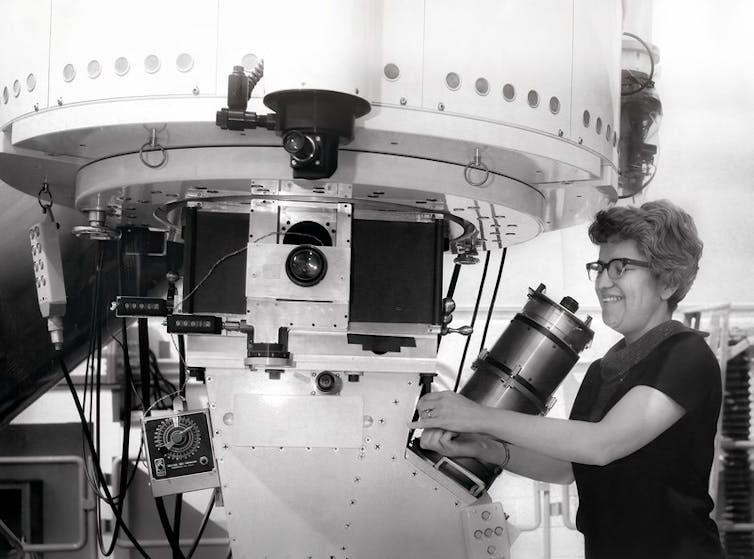 A woman adjusting a large piece of equipment.