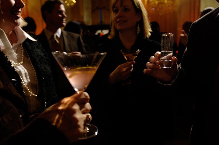 People standing around drinking out of cocktail glasses.