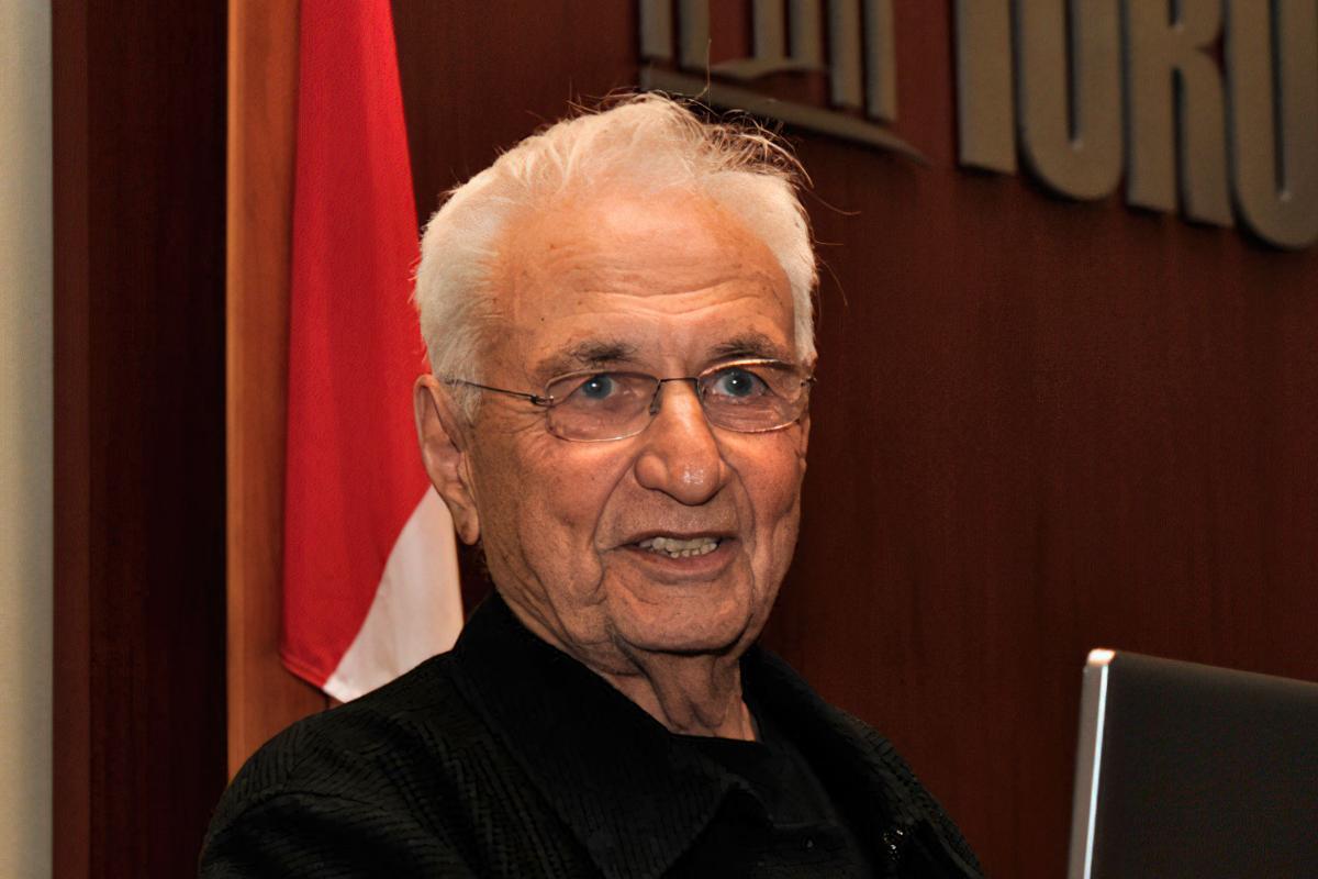 Frank Gehry speaking at the Viljo Revell Centenary reception at Toronto City Hall Chambers, 2010. A man with white hair and glasses looks to the viewer's right.